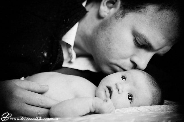 dad kissing newborn daughter portrait