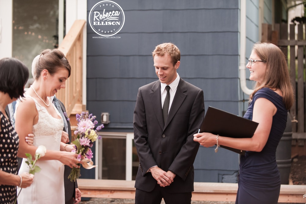 Wedding ceremony at an intimate backyard wedding in Seattle featuring DIY flowers and a whie wedding dress with lace detail photographed by Seattle wedding photographer Rebecca Ellison