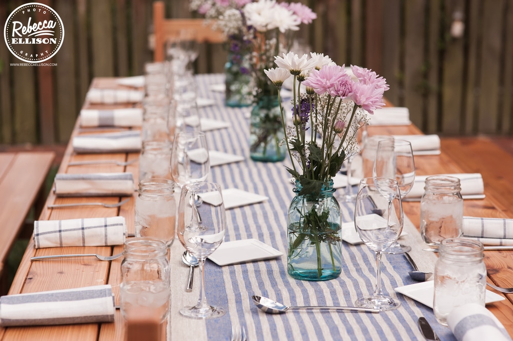 Dinner table at a DIY intimate backyard wedding featuring picnic tables, blue and white table runners and DIY flowers photographed by seattle wedding photographer Rebecca Ellison