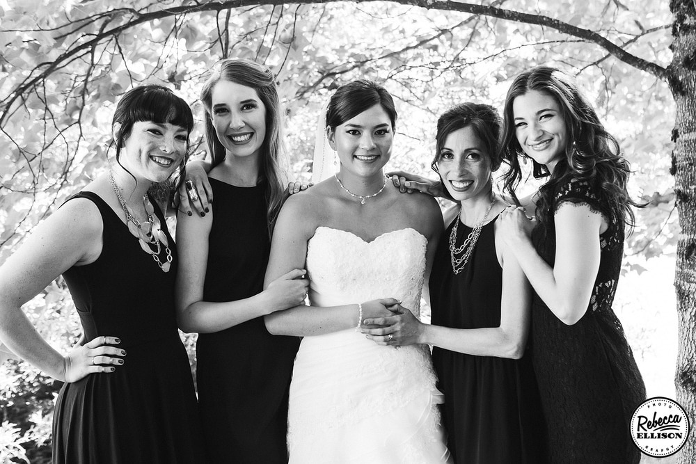 Black and white bridal party portrait during outdoor wedding photos featuring black bridesmaids dresses and white strapless wedding dress photographed by Seattle wedding photographer Rebecca Ellison