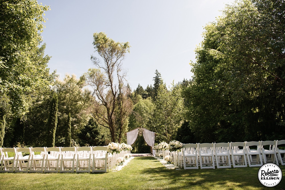 Wedding ceremony at an outdoor garden wedding surrounded by trees on a sunny day photographed by Seattle wedding photographer Rebecca Ellison