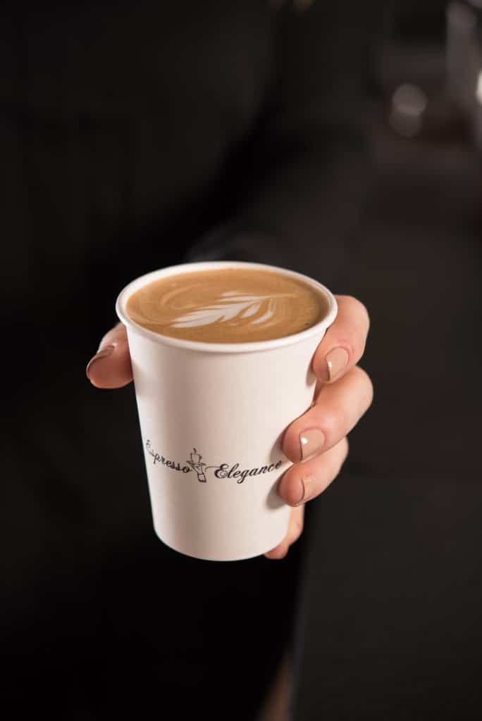 Completed cup of latte being handed over for brand photography in Seattle