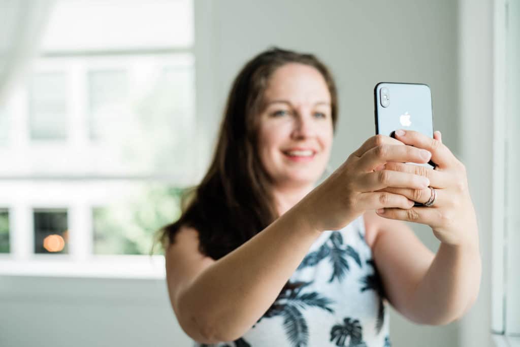 woman holding smart phone camera, taking photos for social media