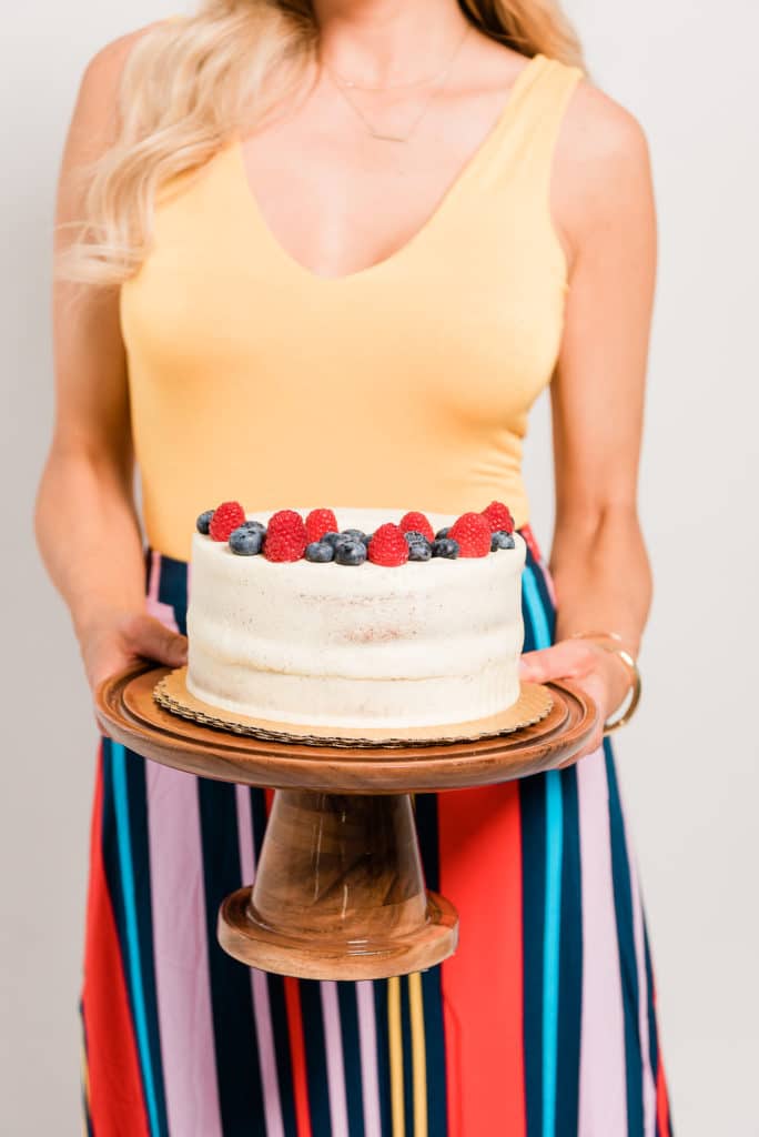 brand photoshoot of Sarah Jio while she is holding a cake  on a cake stand close up